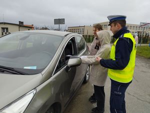 uczniowie stojący przy samochodzie wraz z policjantem