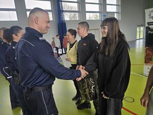 Na zdjęciu znajduje się policjant wręczający nagrody uczestnikom