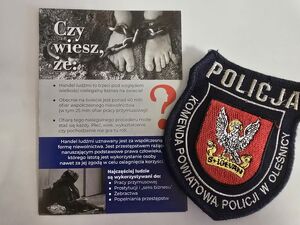 ulotka informacyjna o tematyce handlu ludźmi z herbem oleśnickiej Policji