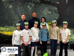 sześcioro dzieci stoi przed policjantami z kaskami ochronnymi na głowach