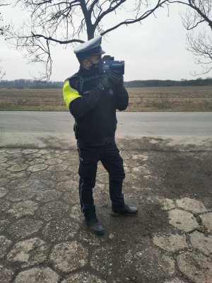 na zdjęciu widać policjanta, który w ręku trzyma miernik prędkości.