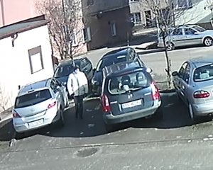 Na zdjęciu widać parking. Na parkingu stoi zaparkowanych kilka pojazdów. Oboko pojazdu marki mazda stoi mężczyzna.